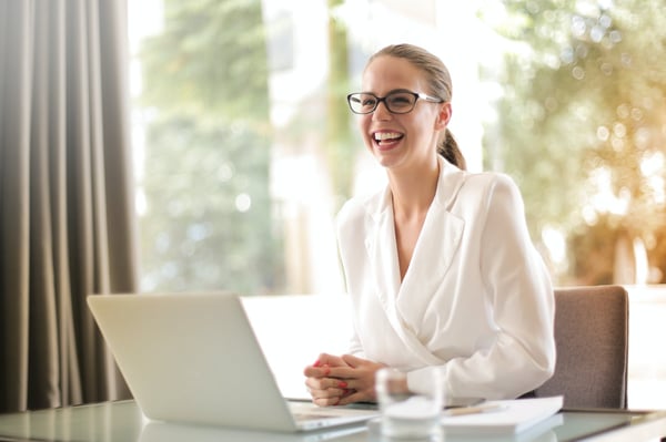 Laughing business woman in office with laptop