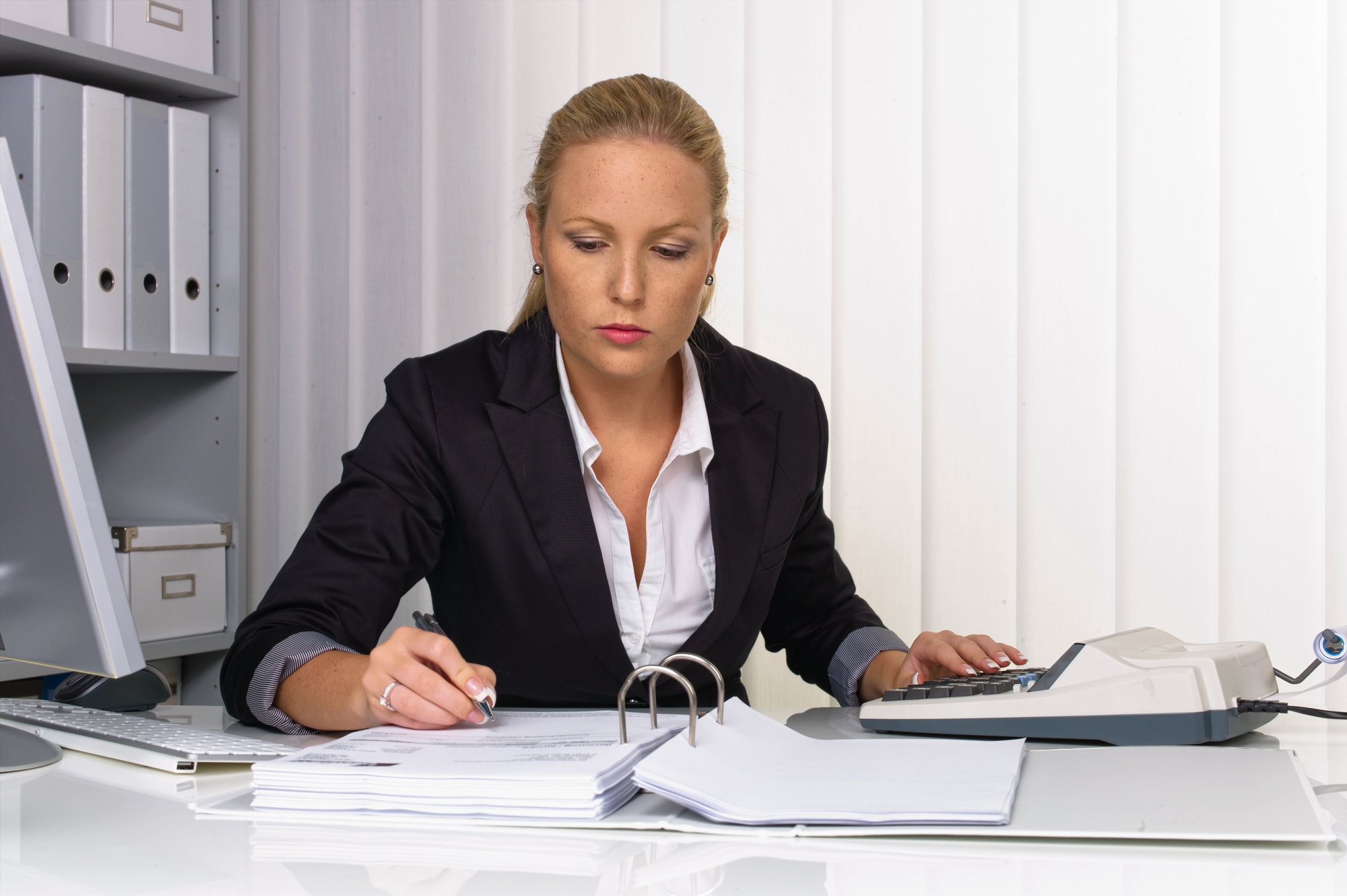 Woman working at her desk going through a binder