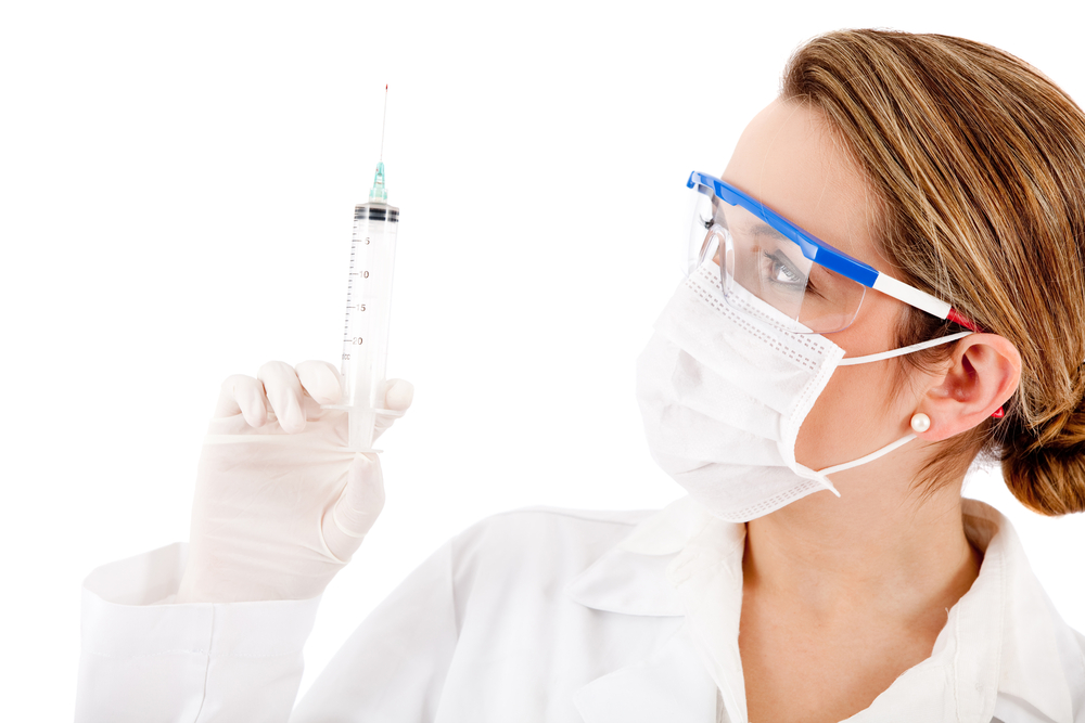 Friendly female doctor with a needle - isolated over white