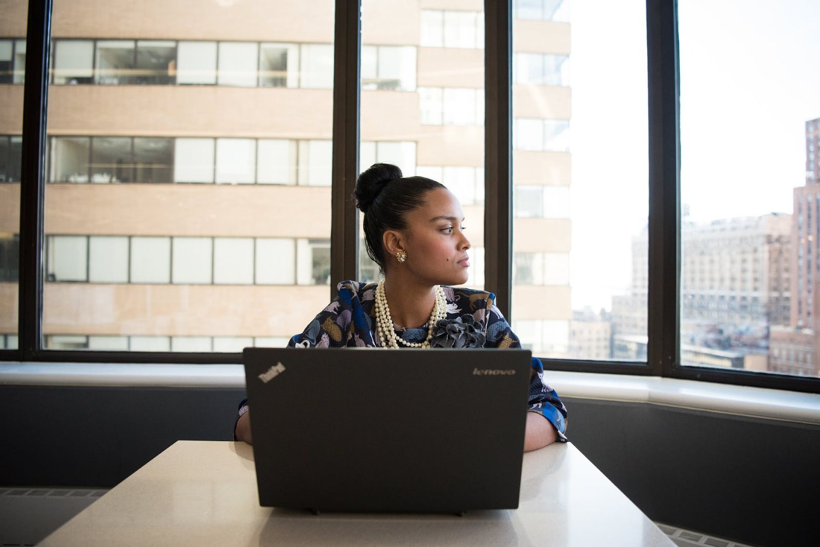 Woman looking out window with laptop